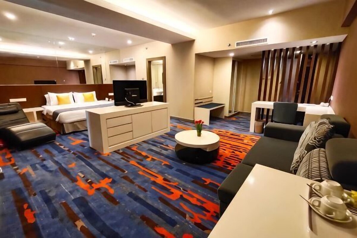 A hotel room with a bed, a TV, a sofa, a coffee table, and a desk.