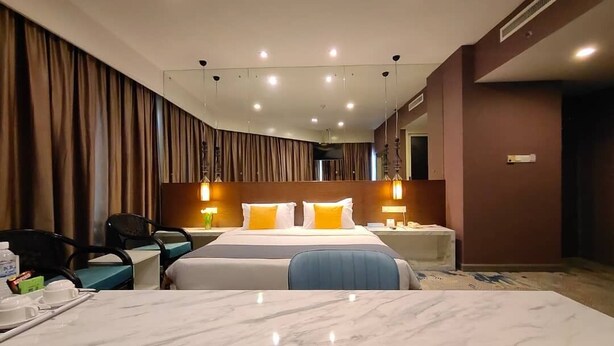 Een hotelkamer met een groot bed, een bureau met stoel, een televisie en een minibar.