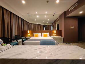 A hotel room with a large bed, a desk with a chair, a TV, and a minibar. - Hotel Capital (Kota Kinabalu)