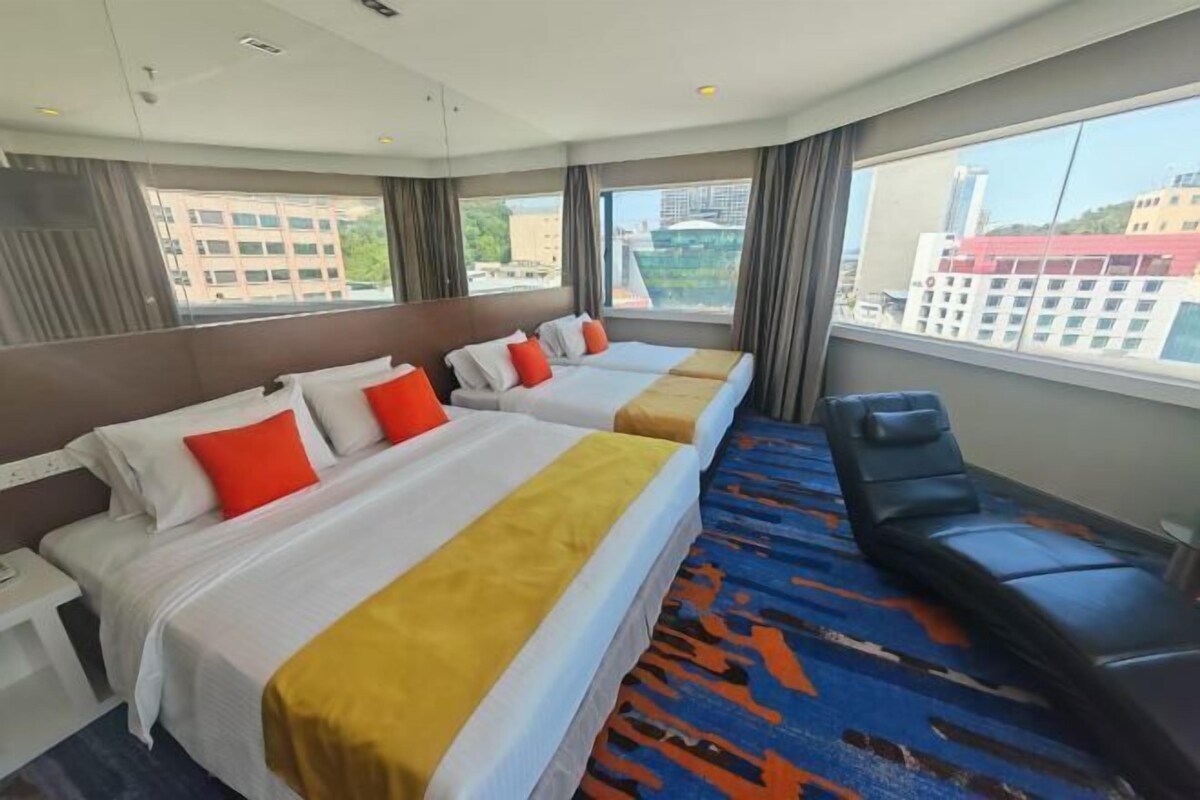 A hotel room with two beds, a sofa, and a large window with a city view.