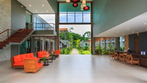 A spacious lobby with a staircase, a reception desk, and a seating area with orange sofas. - Khaolak Forest Resort (Takua Pa)