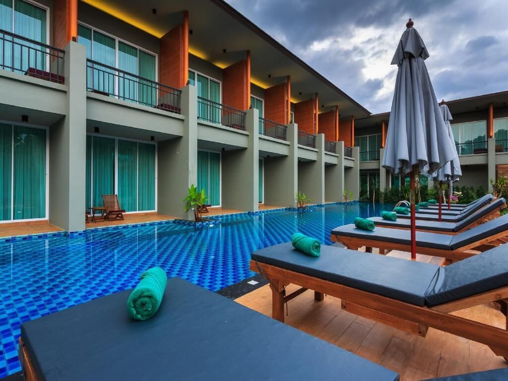 Een hotel met een zwembad, ligbedden en parasols.