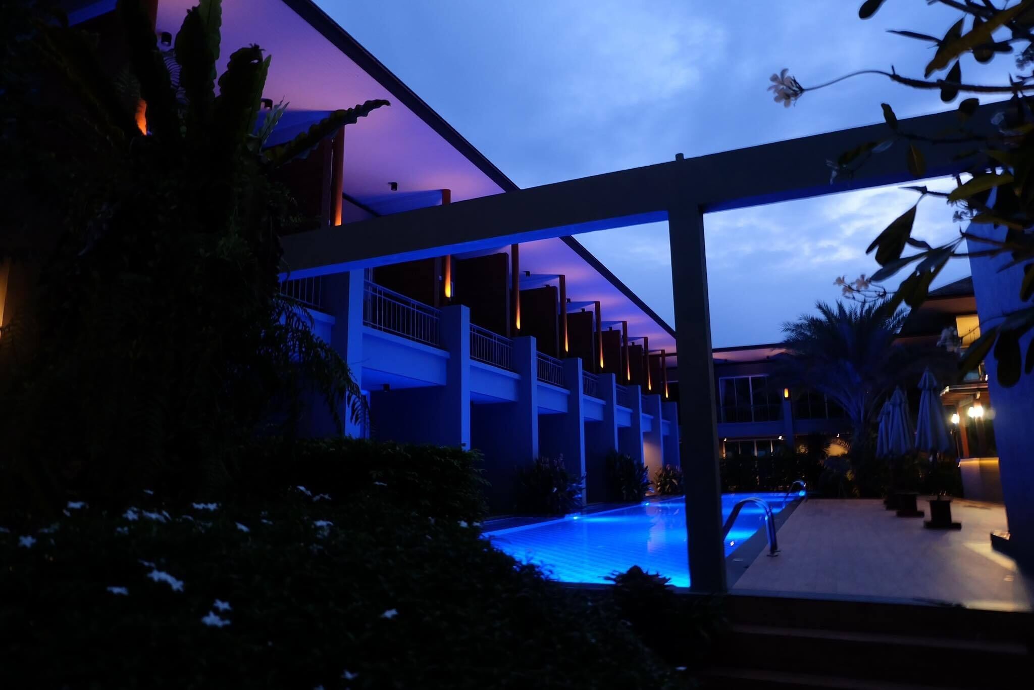 Un hotel moderno con piscina, asientos al aire libre y un paseo cubierto.