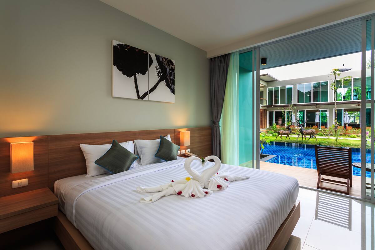 Une chambre d’hôtel avec un grand lit, un tableau au mur, une table de chevet et une vue sur une piscine.
