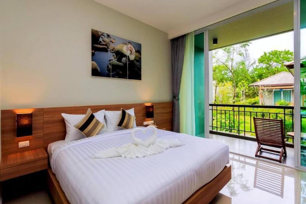 Une chambre d’hôtel avec un grand lit, un tableau au mur et un balcon avec une chaise.