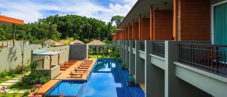 Un hotel moderno con piscina en la azotea, mobiliario de exterior y un exuberante jardín.
