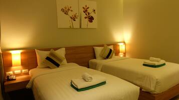 Habitación de hotel con dos camas, cada una con una almohada y una toalla enrollada. Hay lámparas de pared a cada lado de las camas.