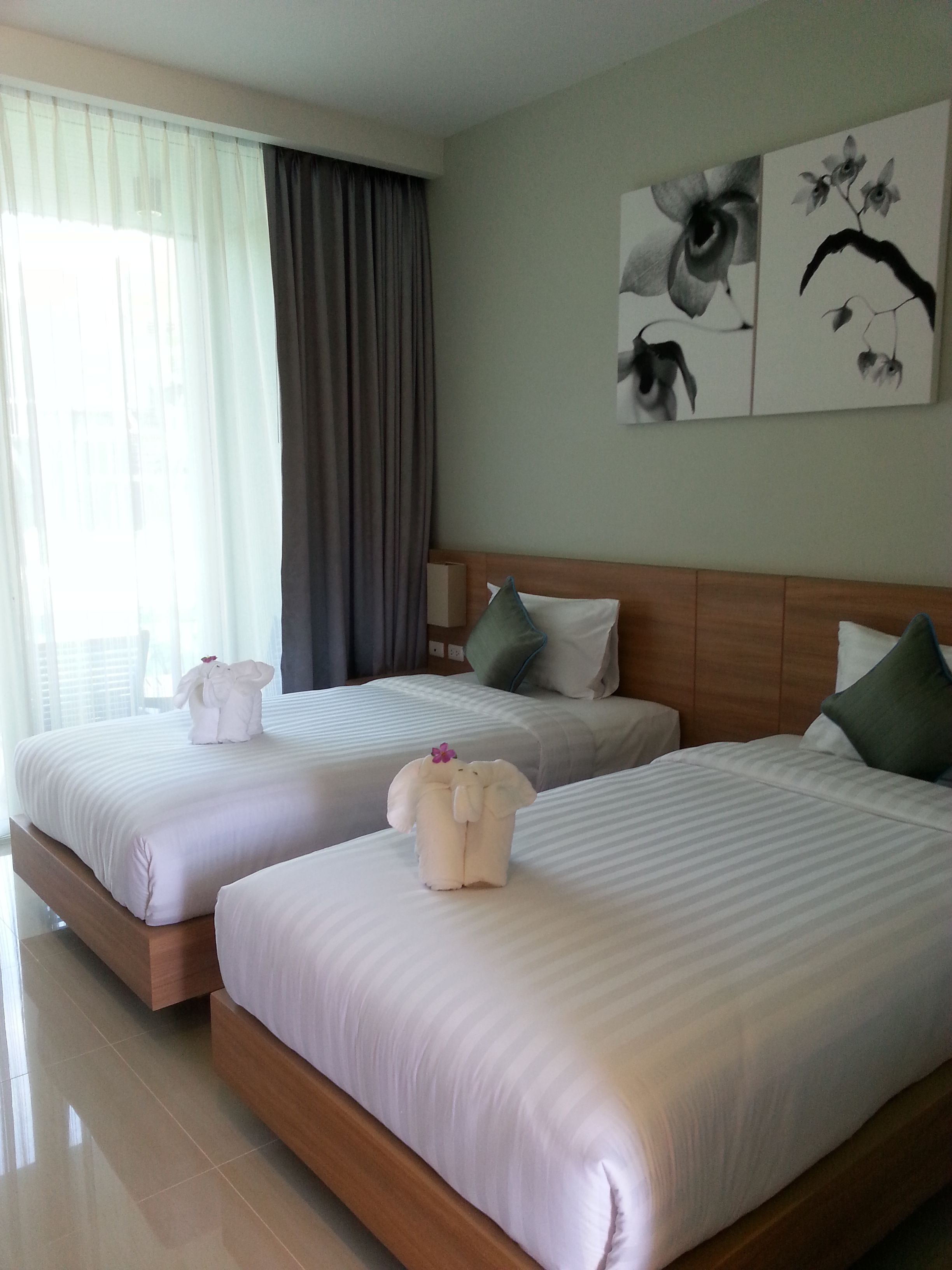 A hotel room with two beds, each with a pillow and a decorative item.