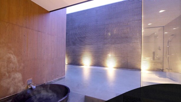 A modern bathroom with a large, round, dark-colored basin and a wooden wall. - Four Seasons Yuzawa Quattro (Yuzawa)