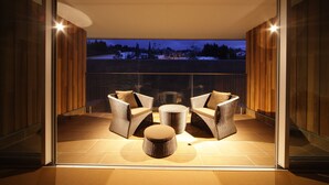 A balcony with wicker furniture and a round table, overlooking a snowy landscape. - Four Seasons Yuzawa Quattro (Yuzawa)