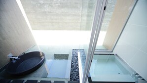A modern bathroom with a glass shower enclosure, a black bathtub, and a small window. - Four Seasons Yuzawa Quattro (Yuzawa)