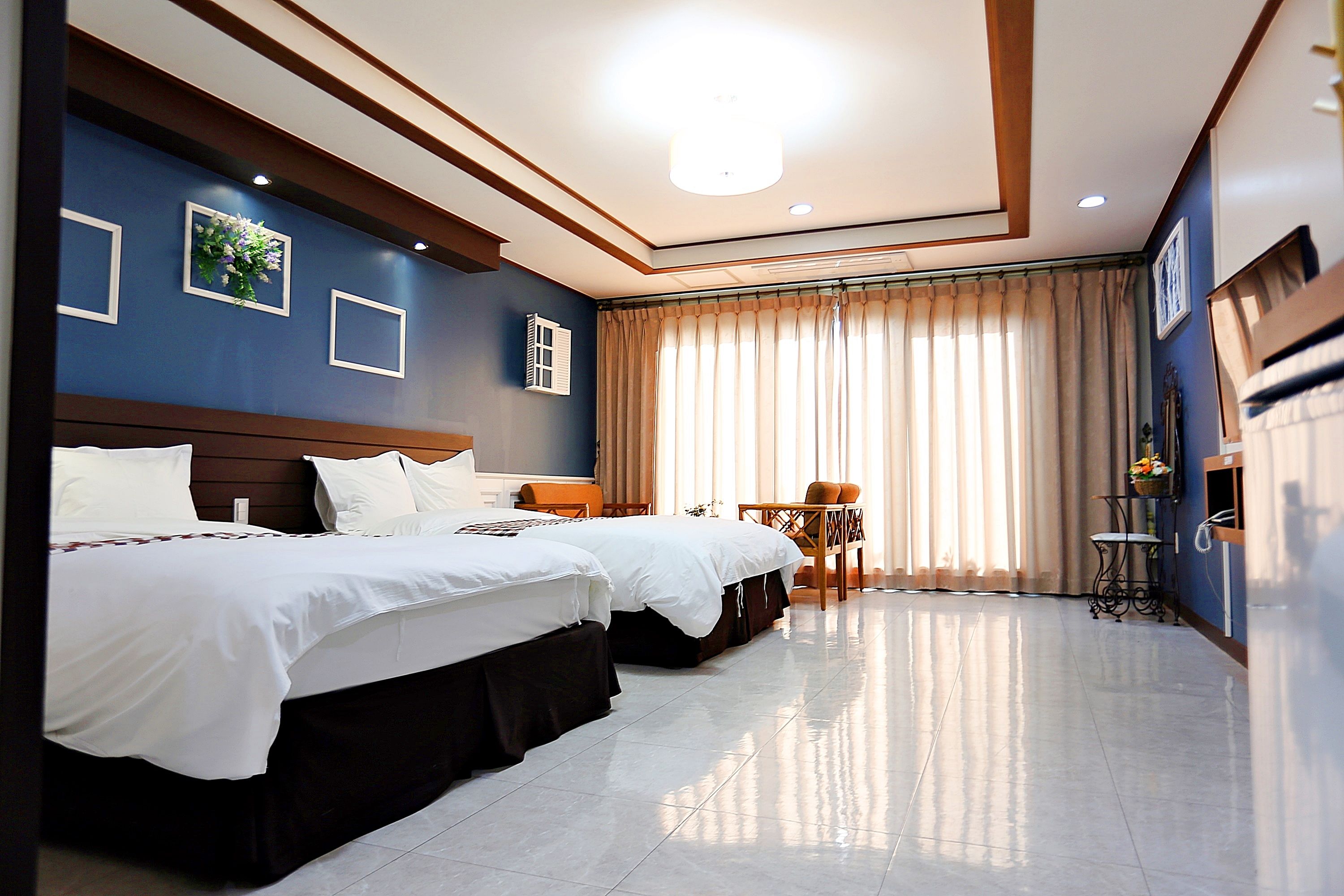 A hotel room with two beds, a desk, and a chair.