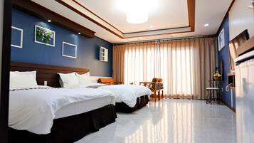 A hotel room with two beds, a desk, and a chair.