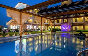 A pool area with a reflection of the building and a dolphin statue. - Famille Spa Resort (Seogwipo)