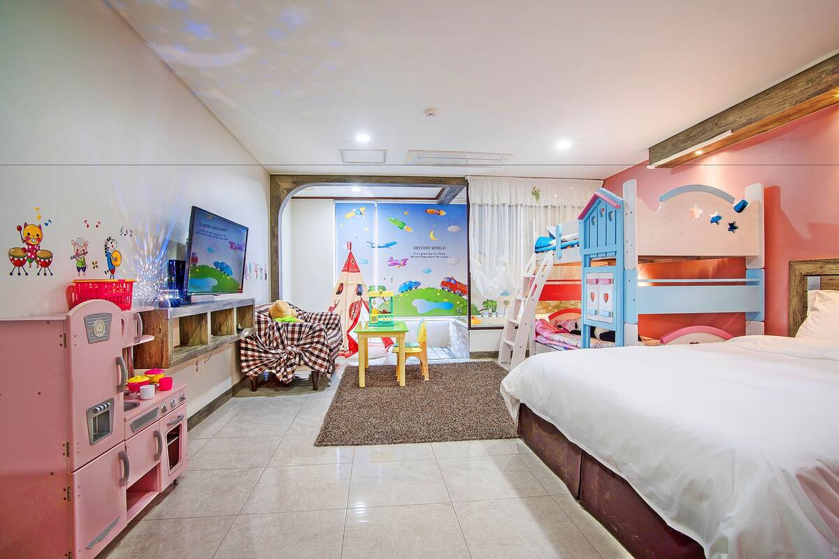 A children's room with a bed, a desk, a chair, a play area, and a television.