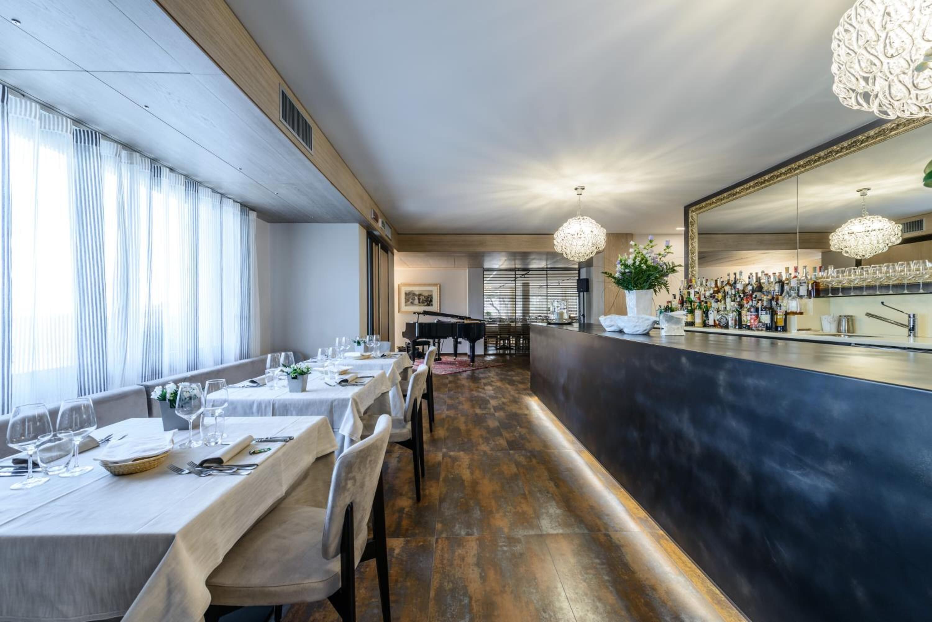 Un restaurante con mesas largas, una barra y un piano al fondo.