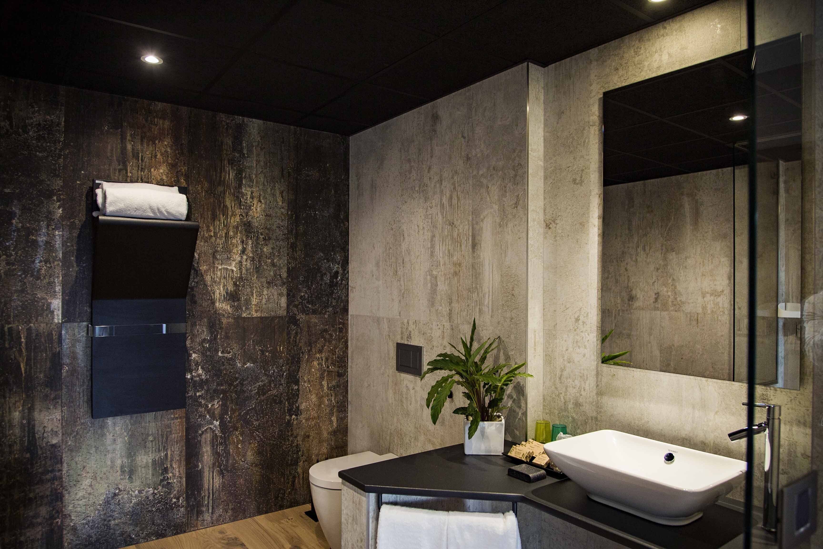 Une salle de bain moderne avec un grand miroir, un lavabo blanc et des toilettes.