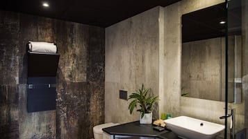 Une salle de bain moderne avec un grand miroir, un lavabo blanc et des toilettes.
