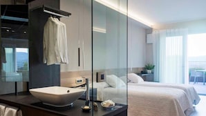 A modern hotel room with a large glass partition, a central sink, a bed, and a balcony with a view. - Ristorante Hotel La Rosina (Marostica)