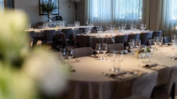 A dining area with multiple tables set for a meal, featuring chairs, wine glasses, and cutlery.