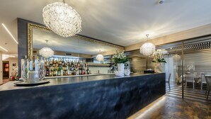 A modern bar area with a dark countertop, decorative chandeliers, and a large mirror. - Ristorante Hotel La Rosina (Marostica)