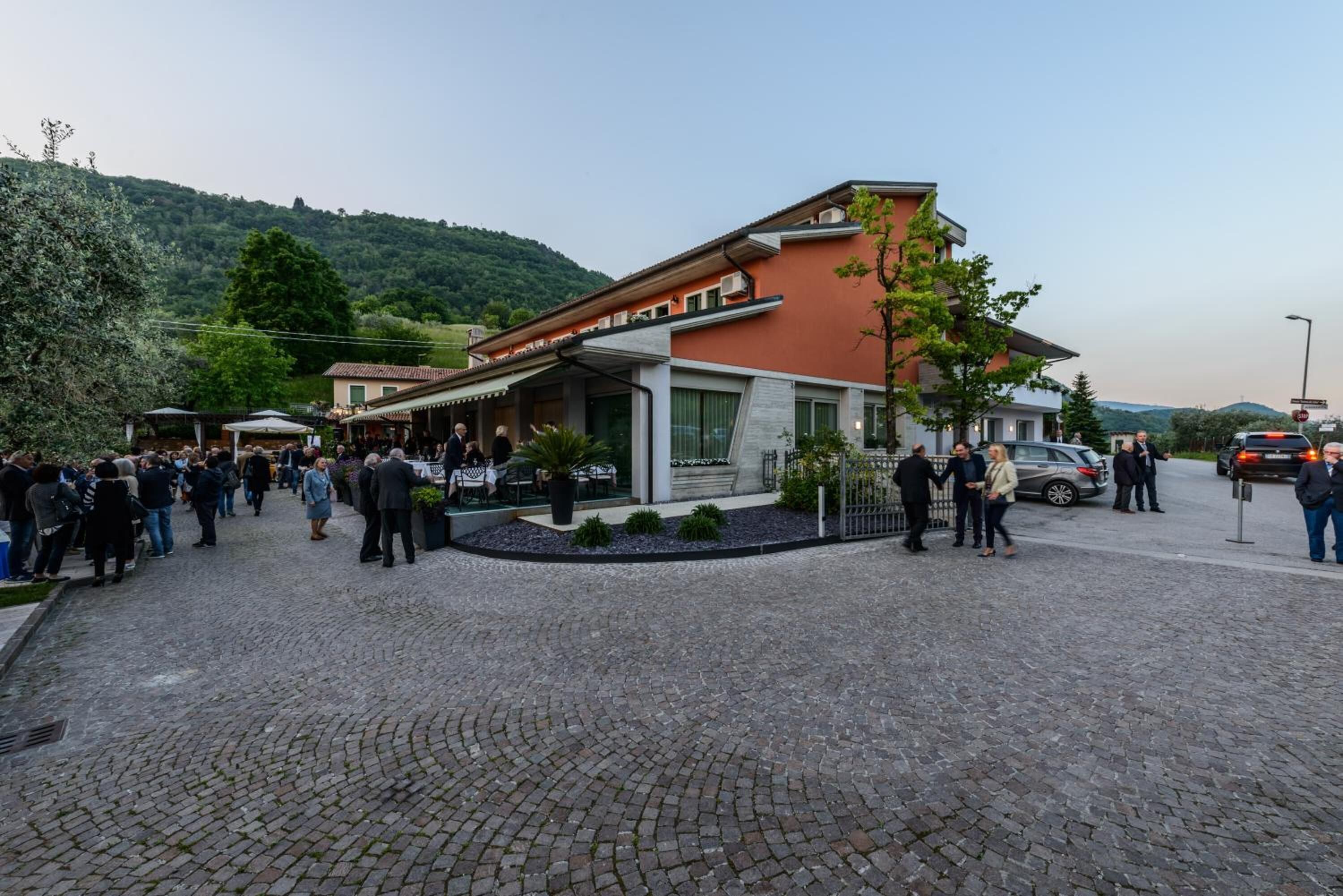 A building with a red facade, a covered outdoor seating area, and a cobblestone courtyard.