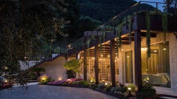A modern building with a staircase leading to a second floor, surrounded by lush greenery and well-lit outdoor areas. - Ristorante Hotel La Rosina (Marostica)