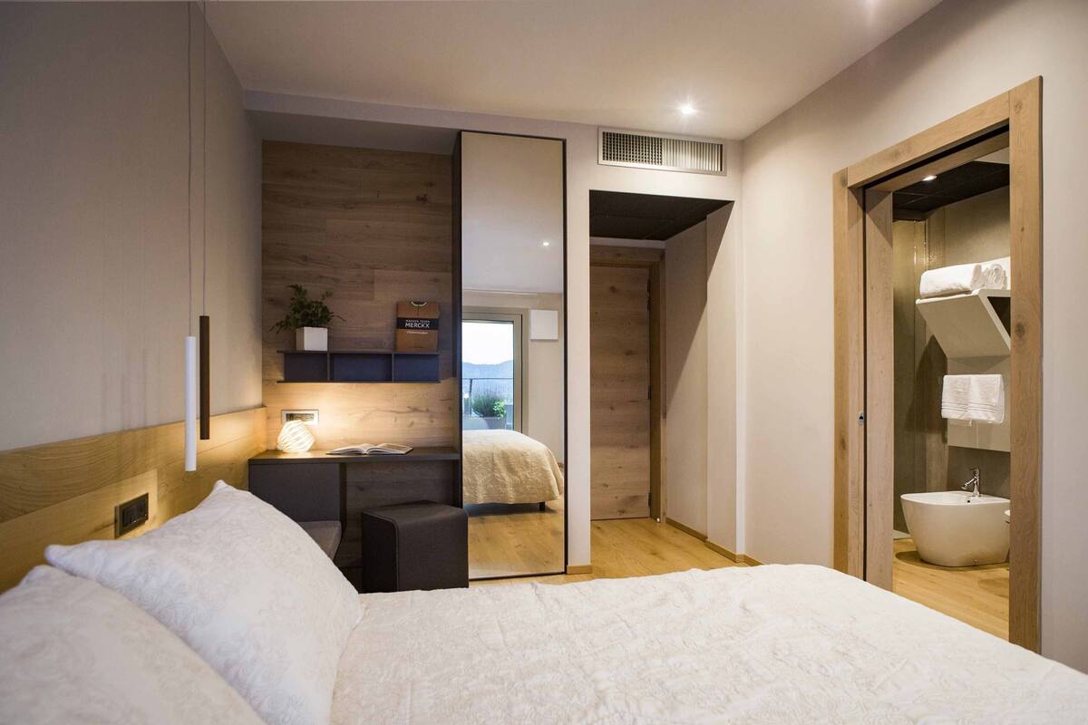 A modern bedroom with a bed, bedside table, and a large mirror.
