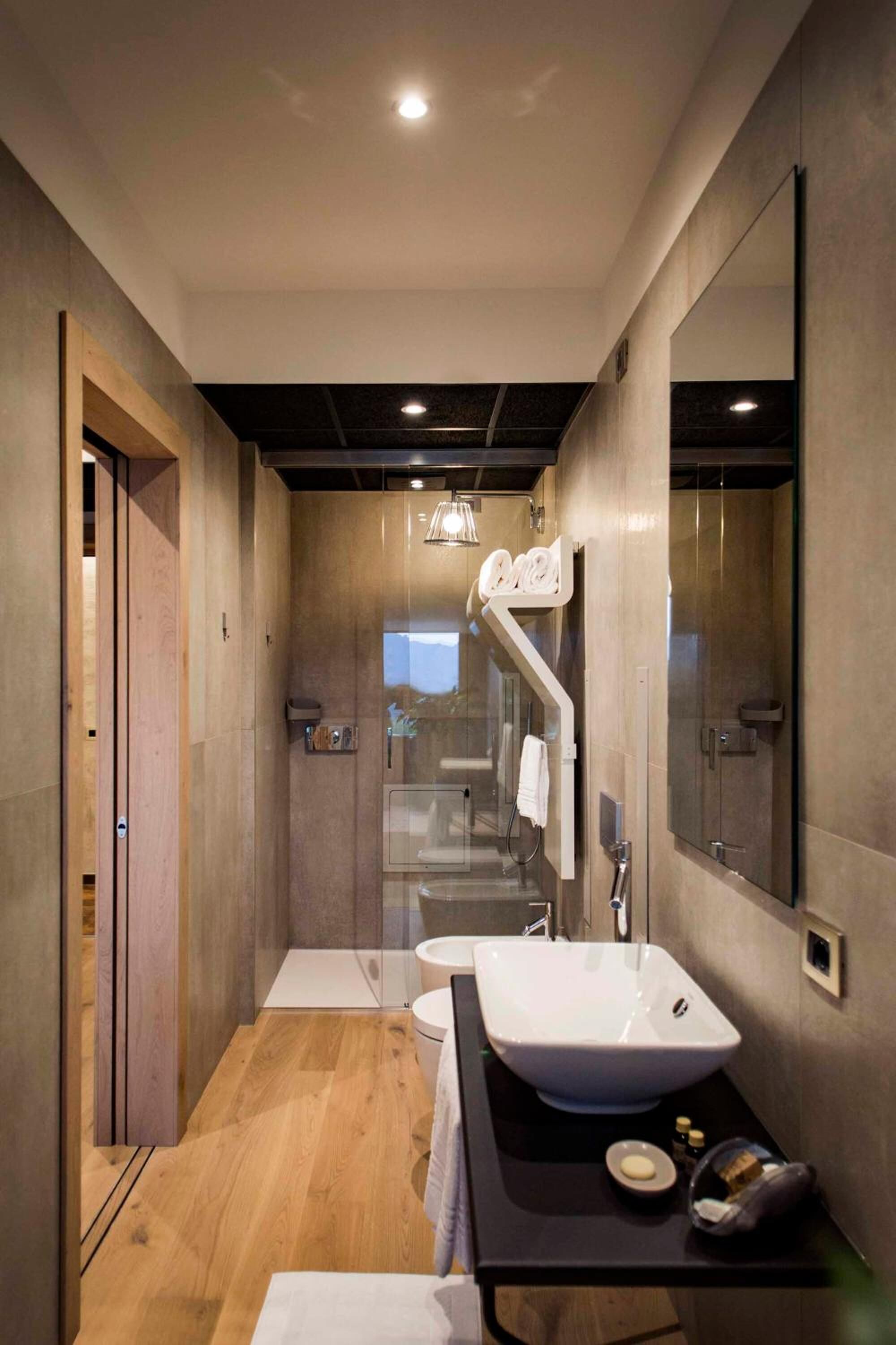 A modern bathroom with a large mirror, a white sink, and a glass shower enclosure.