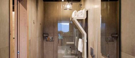 A modern bathroom with a large mirror, a white sink, and a glass shower enclosure.