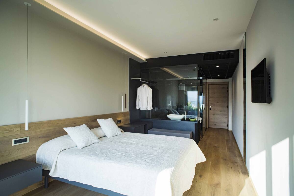 A modern bedroom with a large bed, a bedside table, and a built-in bench.