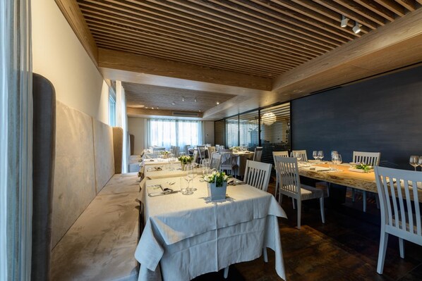 A modern dining area with wooden ceiling beams, white tables, and chairs.
