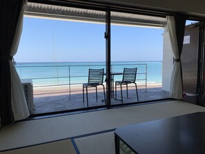 A balcony with two chairs and a table, overlooking a beach and the ocean. - On The Beach Lue (Motobu)