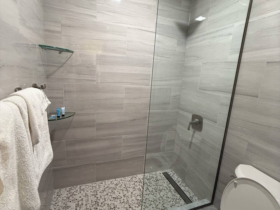 A modern bathroom with a glass-enclosed shower, a toilet, and a towel rack.