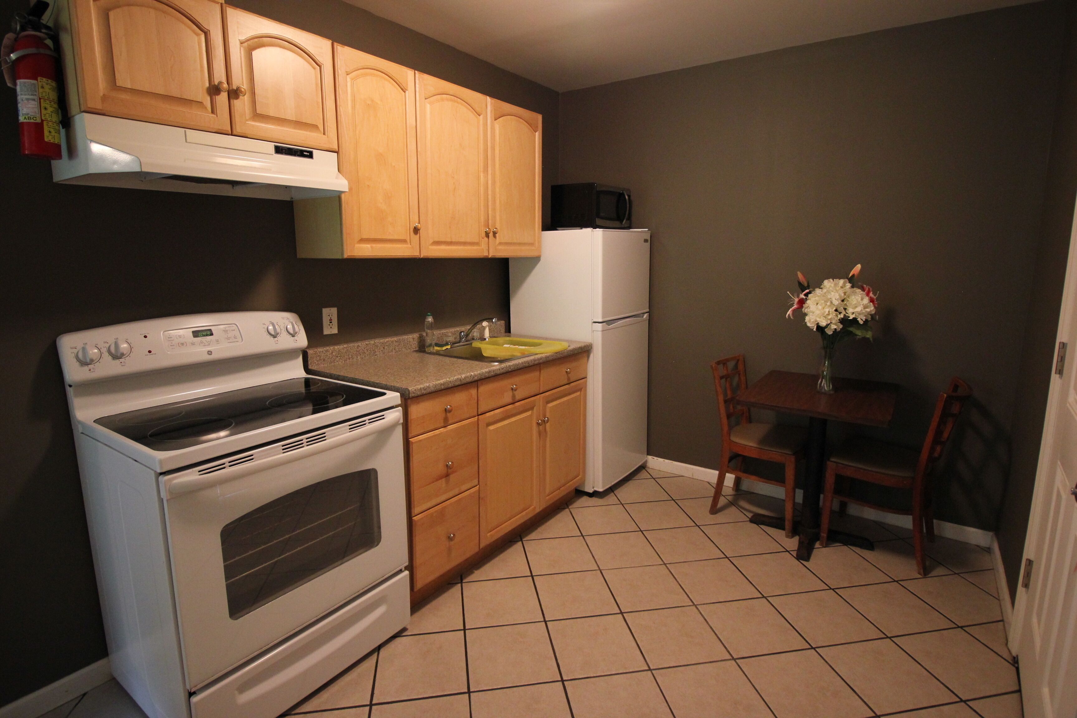 A kitchen with wooden cabinets, a white stove, a white refrigerator, and a dining table with chairs.