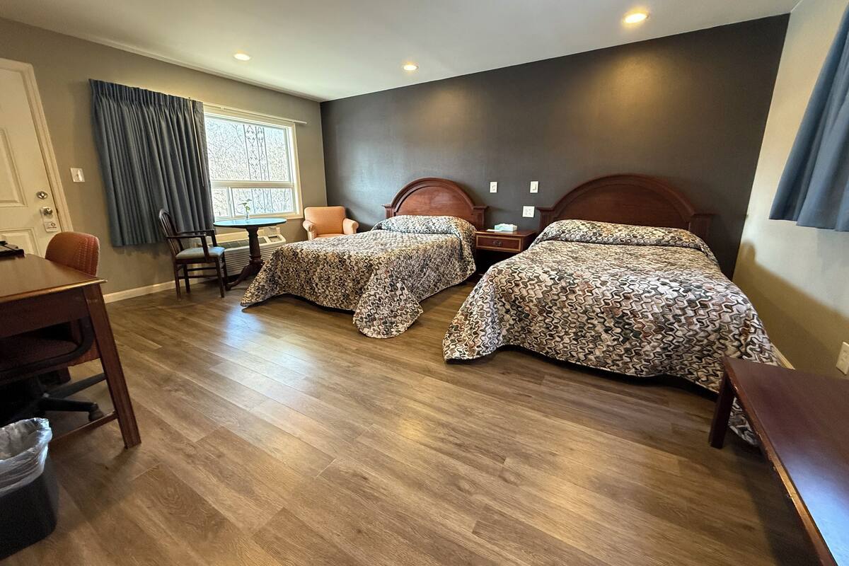 A hotel room with two beds, a dining table, and a chair.