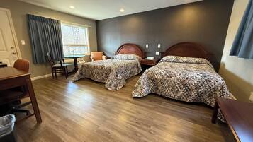 A hotel room with two beds, a dining table, and a chair.