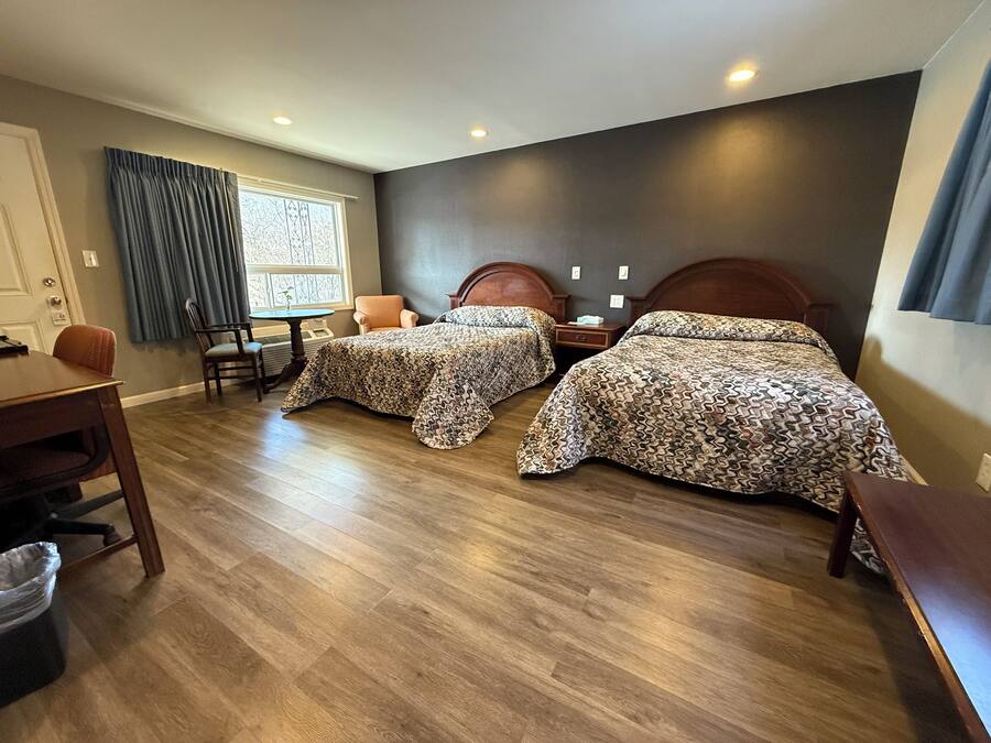A hotel room with two beds, a dining table, and a chair.