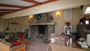 Una sala de estar acogedora con chimenea de piedra, muebles de madera y una estación de café.