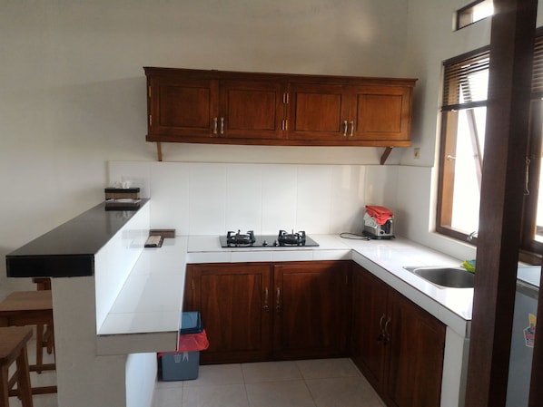 Una cocina con armarios de madera, encimera blanca, estufa a gas y un tostador.