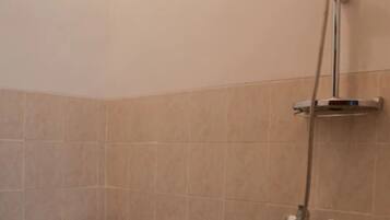 Un bagno con il water, una doccia e uno scaffale a parete.