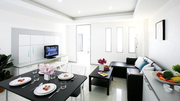 A modern, well-lit living room with a dining area, a flat-screen TV, and a sofa. - The Grand Suree Residence (Bangkok)