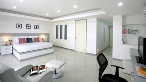 A modern bedroom with a large bed, a desk with a computer, and a chair. - The Grand Suree Residence (Bangkok)