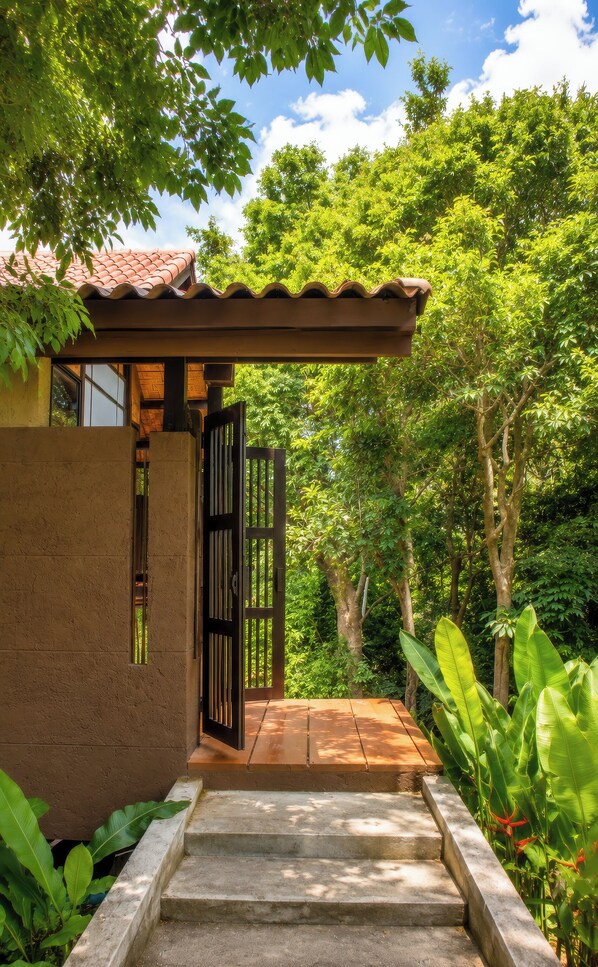 A wooden deck leading to a building with a tiled roof, surrounded by lush greenery. - Alama Sea Village Resort (Ko Lanta)