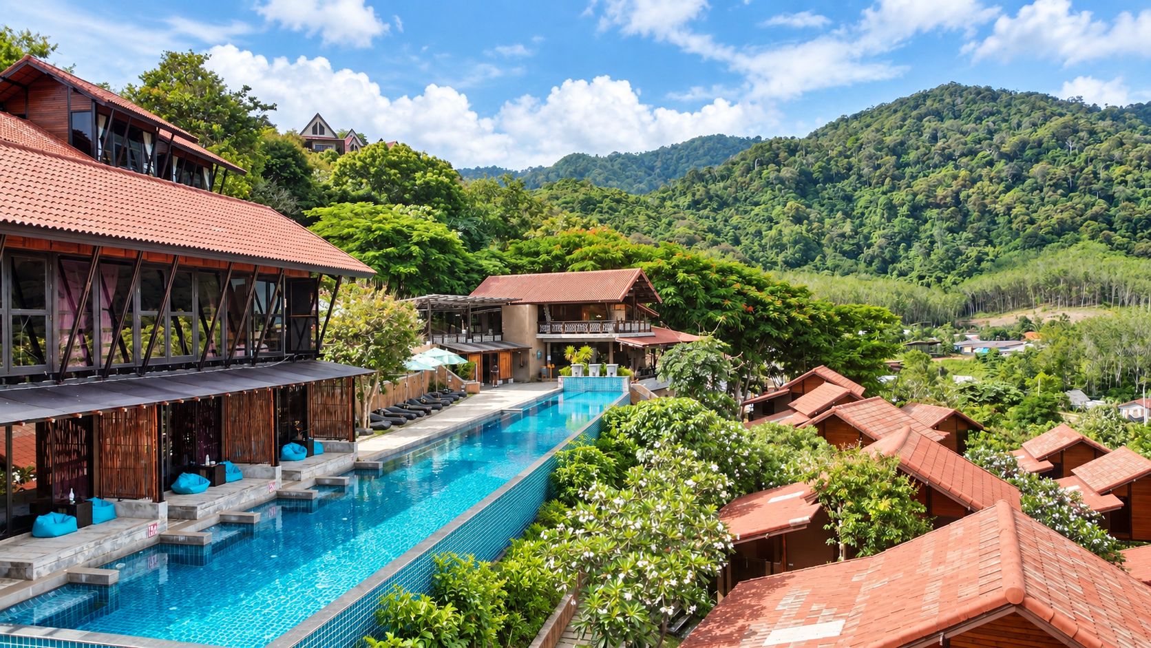 Un resort con piscina, edificios de madera y abundante vegetación.