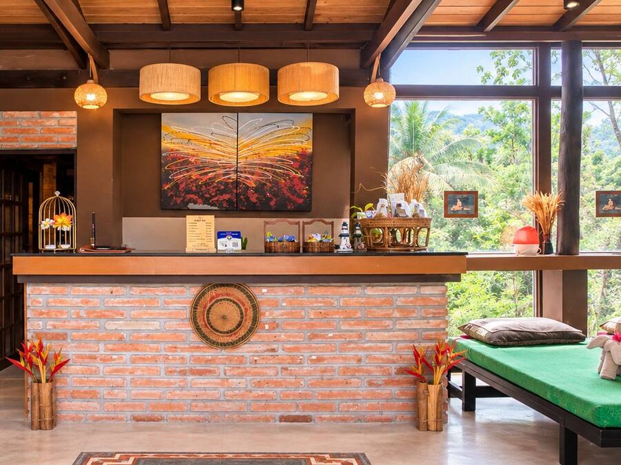 A reception area with a brick wall, a green sofa, and a large window with a view of greenery.