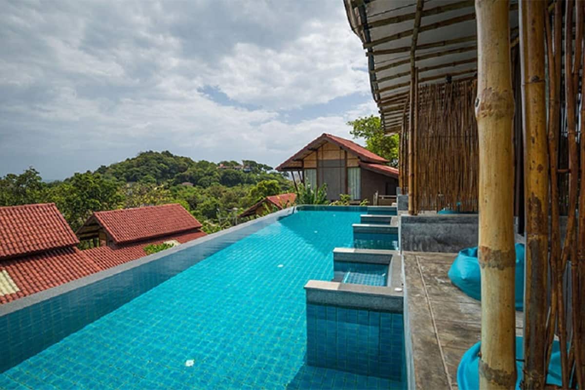 A swimming pool with a view of a building and greenery in the background.