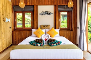 A hotel room with a bed, two windows, a wall-mounted fish decoration, and a wooden wall. - Alama Sea Village Resort (Ko Lanta)