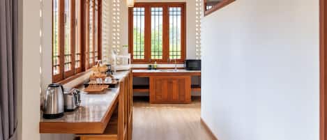 Une cuisine avec des meubles en bois, un plan de travail en marbre et une vue sur la verdure à l’extérieur.
