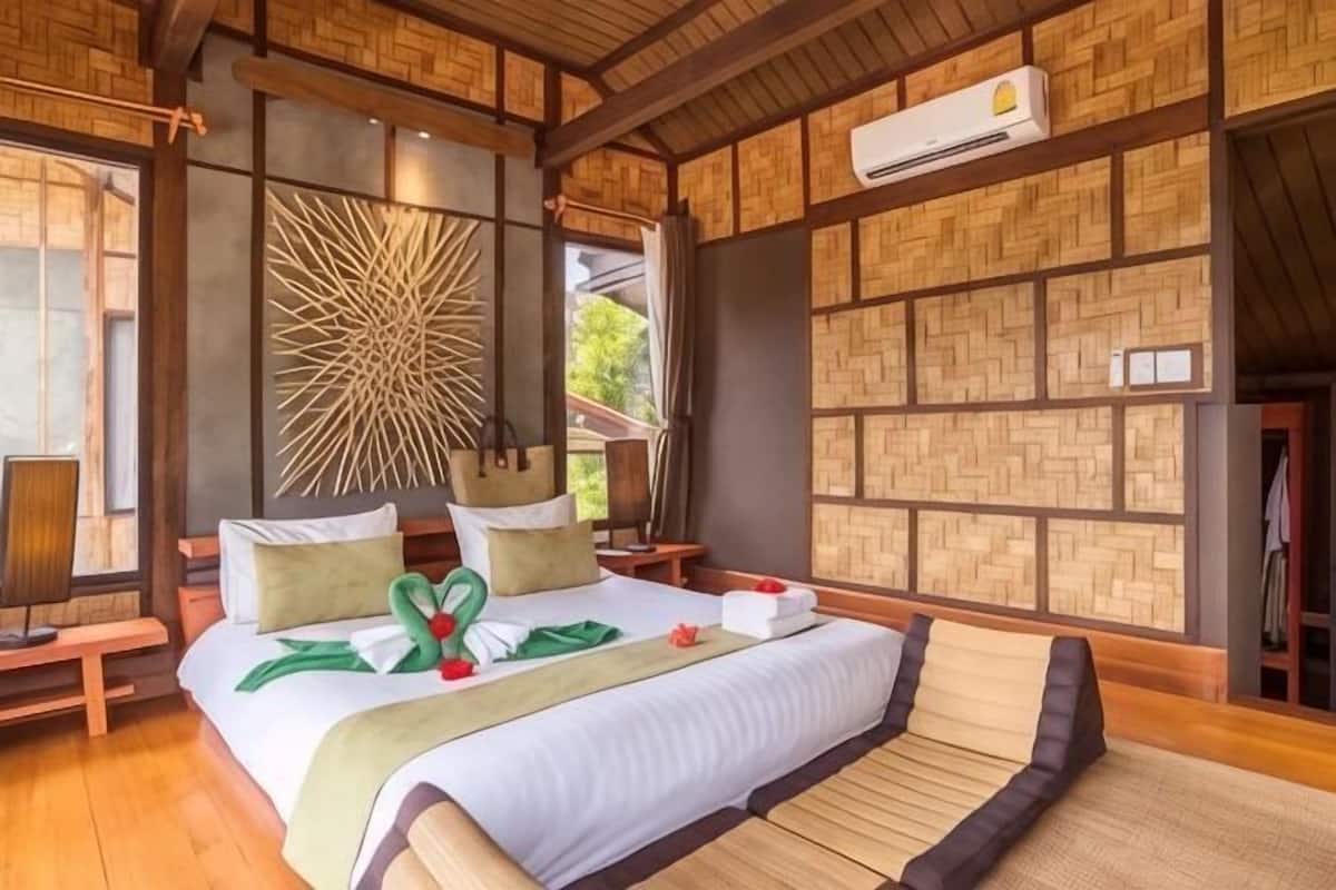 A room with a bed, a wall-mounted air conditioner, and a large window.